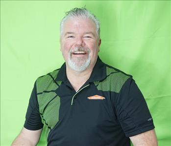 Male employee with gray hair in front of green background
