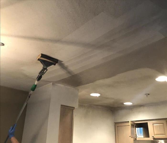 Employee cleaning soot from ceiling