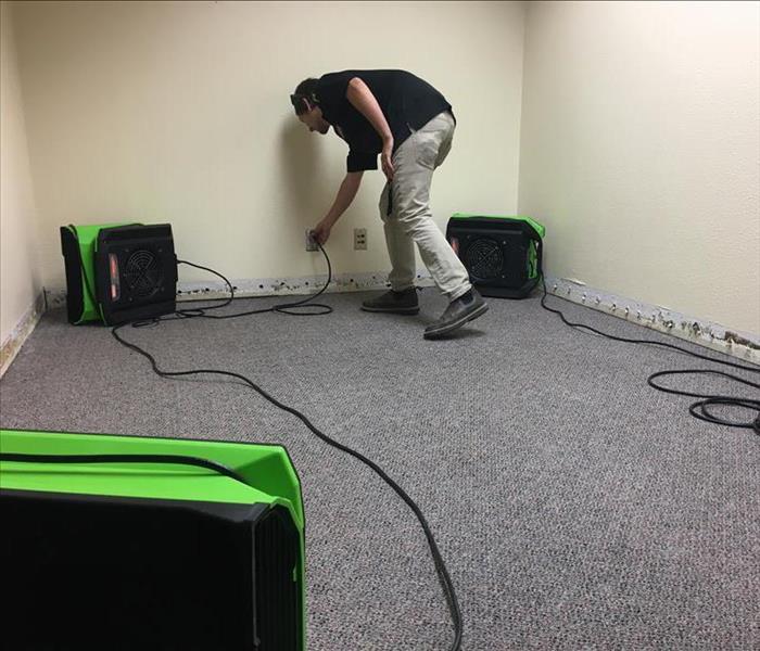 Water damaged office with Servpro tech setting up fans